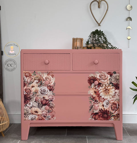 Pink dresser with floral design in a room setting with decor elements.