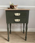 Green side table with wooden top against a gray wall