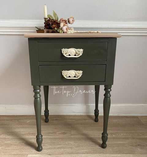 Green side table with wooden top against a gray wall