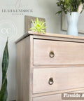 Wooden dresser with 'Fireside Ash' finish in a room with plants and decor.
