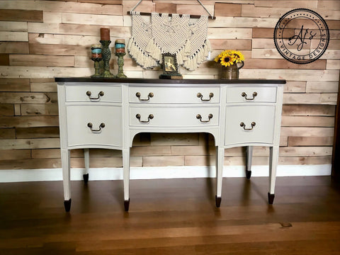 Grayish white painted dresser makeover with dark brown feet and top and bronze pulls. Staged with candlesticks, a picture frame and sunflowers on top.
