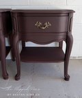 Pair of dark wood nightstands against a white brick wall.