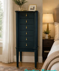 Dark green jewelry armoire with gold knobs in a bedroom setting, featuring 'Creative Moments' text.