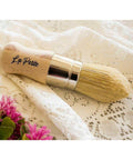Belles and Whistles La Petite Brush is excellent for detailing and highlighting your project. La Petite Brush on a white lace cloth and flowers off to the side.
