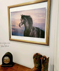 Majestic Horse decoupage paper in a gold frame, hung on the wall. Staged with cowboy boots and an old clock on the table below it.