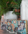 Four decorative Christmas blocks featuring whimsical designs using the Nordic Noel Decoupage Paper, including trees and animals, placed under potted pine trees.
