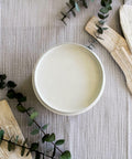 Baja Gray Silk All-In-One Mineral Paint is perfect for painting kitchen cabinets, bathroom cabinets and painting furniture. Image shows a top view of an opened container of  Baja Gray Silk All-In-One Mineral Paint staged on a plaid tablecloth with sticks of palo santo and green branches.