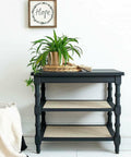 Black Sands Silk All-In-One paint is perfect for painting kitchen cabinets, bathroom cabinets and painting furniture. Entry table with two white rattan shelves below Painted with Black Sand Silk all in one mineral paint. Staged in white walled room with gold planter with faux air plants hanging out and off furniture in a woven basket.