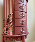 Desert Rose Silk All-In-One paint is perfect for painting kitchen cabinets, bathroom cabinets and painting furniture
Here is a large, tall, 5 drawered, three-legged jewelry piece of furniture.  It is painted in Desert Rose CMP.  There are appliques on the bottom of the furniture and Decoupage on side of the piece.  The side is painted in stripes with Desert Rose alternating with Soft Pink CMP.  This piece of furniture is up against a light green wall.