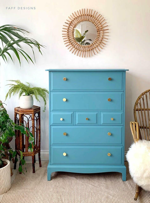 Harbor Silk All-In-One paint is perfect for painting kitchen cabinets, bathroom cabinets and painting furniture.
Chest of drawer painted in Harbor Silk All-In-One paint with gold hardware, staged with potted greenery on one side and a rocking chair with the white fur blanket on the other.