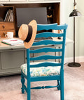 Oasis Silk All-In-One paint is perfect for painting kitchen cabinets, bathroom cabinets and painting furniture. Blue chalk painted chair with floral fabric on the seat. Staged in front of a desk with a hat on the top of chair.