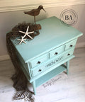 Tide Pool Silk All-In-One paint is perfect for painting kitchen cabinets, bathroom cabinets and painting furniture.  A blue chalk painted corner table with a wooden bird, star fish and a fishing net sitting on top and around; with black knobs.