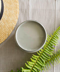 Wharf Silk All-In-One paint is perfect for painting kitchen cabinets, bathroom cabinets and painting furniture.  Top view of an open jar of Wharf Silk All-In-One paint sitting on a tan and brown piece of cloth.  A light brown woven hat with a black band sits to the left of the jar, and a two green fern branches are to the right of the jar.