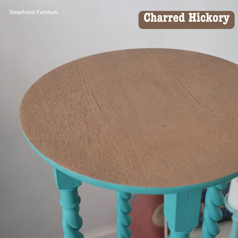 Round wooden table with a natural top and teal-painted twisted legs. "Sisterhood Furniture" and "Charred Hickory" are written on the image.