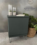 Bluish gray cabinet transformation with metal feet. Staged with two clear tall vases containing pebbles and faux succulents and a cookbook placed on top.