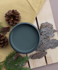 Overhead shot of an open jar of Smoky Mountains on a wood pallet with faux greenery, pine cones, and bark.