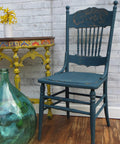 Blue Agave Terra Clay Paint provides endless possibilities for your imagination and can be used on wood, canvas, tile, fabric and more! Vintage wooden chair painted in Blue agave Terra Clay Paint with distressed accent. Staged in front of a white brick wall next to yellow hallway table and empty blue glass vase.