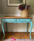 Cerulean Blue Terra Clay Paint provides endless possibilities for your imagination and can be used on wood, canvas, tile, fabric and more!
Console tbale painted in Cerulean Blue Terra Clay Paint with a light brown wood top. Staged with a woven basket and flowers.