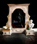 Desert Tan Terra Clay Paint provides endless possibilities for your imagination and can be used on wood, canvas, tile, fabric and more!
This is a stone surround for a  fireplace painted in Desert Tan Terra Paint.  There is an applique on the bottom of the piece.  It rests on a very dark cement floor and black background.  It is staged with a Greek Bust, dried flower in a green vase and a couple books, one which is splayed open.