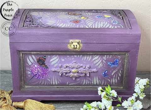 Elderberry Terra Clay Paint provides endless possibilities for your imagination and can be used on wood, canvas, tile, fabric and more! Purple clay painted jewelry chest with a gold lock. Wildflowers & Butterflies rub on furniture transfer applied on the chest. In the open space, the Botanical Silkscreen Stencil was applied using Chameleon Wax.
