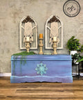 Lani's Lagoon Terra Clay Paint provides endless possibilities for your imagination and can be used on wood, canvas, tile, fabric and more!
A chest painted with a blend of Elderberry, Blue Moon, Lani’s Lagoon, and Daffodil all from the Terra Clay Paint line , with the WoodUBend Applique #1323.26 is seen in the center of the pieces painted with Lani's Lagoon Terra Clay Paint. Staged with candle pedestal and greenery.