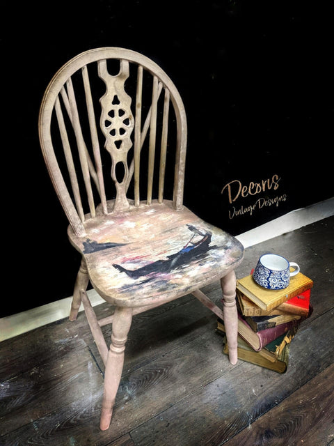 Moon Beam Terra Clay Paint provides endless possibilities for your imagination and can be used on wood, canvas, tile, fabric and more! Chair Painted cream with terra clay paint with Man in Gondola Decoupage paper. Staged next to a stack of books.
