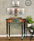 Onyx Terra Clay Paint provides endless possibilities for your imagination and can be used on wood, canvas, tile, fabric and more! End table painted Rainbow Ombre on the front with Terra Clay paint and black clay paint on the legs. Staged with book with candle sticks and candles on top and some plants in white pots besides it.