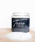 Terra Clay Paint Terra Clean.  A jar of Terra Clay Paint Terra Clean sitting on a table with the lid off and a pile of Terra Clean on the table.