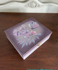 Wisteria Mist Terra Clay Paint provides endless possibilities for your imagination and can be used on wood, canvas, tile, fabric and more!  A small wooden box that has been chalk painted with purple and Wisteria Mist Terra Clay Paint.  The Translucent Garden Transfer is applied to the center of the top of the box, and the clasp is gold.  The box sits on a brown wooden table, in front of a white wall.
