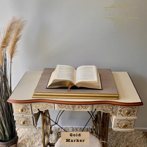Decorative table with an open book on top, featuring intricate designs and a gold marker label.