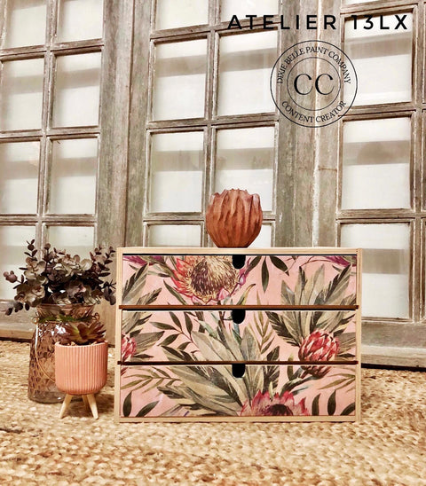 Belles and Whistles Tropical on Pink - Rice Decoupage Paper.  Small chest of drawers with the tropical On Pink Rice Decoupage Paper on front, staged with two planters on the left, one with cactus and one with dried floral arrangement