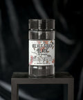 A container labeled "Velvet Touch Black, 30 grams" sits on a black square stand against a dark, velvety background. The label includes floral designs and a warning: "Do not get wet."