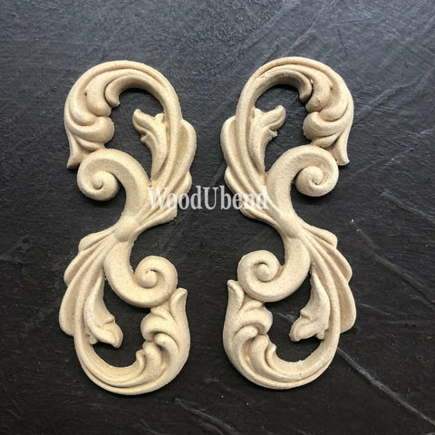 WoodUBend Applique #2150 (Set of 2) is the perfect mouldable embellishment for any project!
Applique #2150 (Set of 2) is seen side by side staged on top of a black crinkled background.