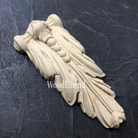 WoodUBend Applique #6076 (Set of 2) is the perfect mouldable embellishment for any project!
One of the Applique #6076 (Set of 2) out of the packaging staged on a black crinkled background.
