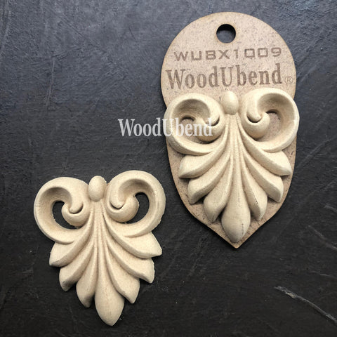 WoodUBend Applique #X1009 is the perfect mouldable embellishment for any project!
Image of two Applique #X1009 is seen displayed flat and staged on a black crinkled background.