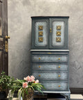 WoodUBend Floral Applique #2427 (set of 2) is the perfect mouldable embellishment for any project!
A chest of drawer with a cabinet at the top, on the cabinet doors you can see 3 Floral Applique #2427 on both sides going down in the middle. Staged with a bronze pot with greenery and flowers in front of the piece.