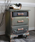WoodUBend Gear Collection Appliques #56 is the perfect mouldable embellishment for any project!
Bedside table with the bottom drawer in Gear Collection Appliques #56 on either side of the copper hardware. Staged on top of the table are books and leaning on the piece is a large branch.