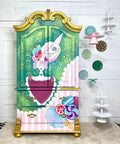 WoodUBend Keyhole #987 is the perfect mouldable embellishment for any project!
A child's wardrobe with a whimsical child candyland painting and design. The wardrobe has Keyhole #987  on the furniture piece. Staged on the walk next to the piece are ceramic plates as well as hanging cupcake and cake stands.